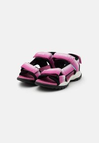 Pink children's sandals with hook-and-loop straps, black accents, a textured footbed, and a textured black rubber outsole.