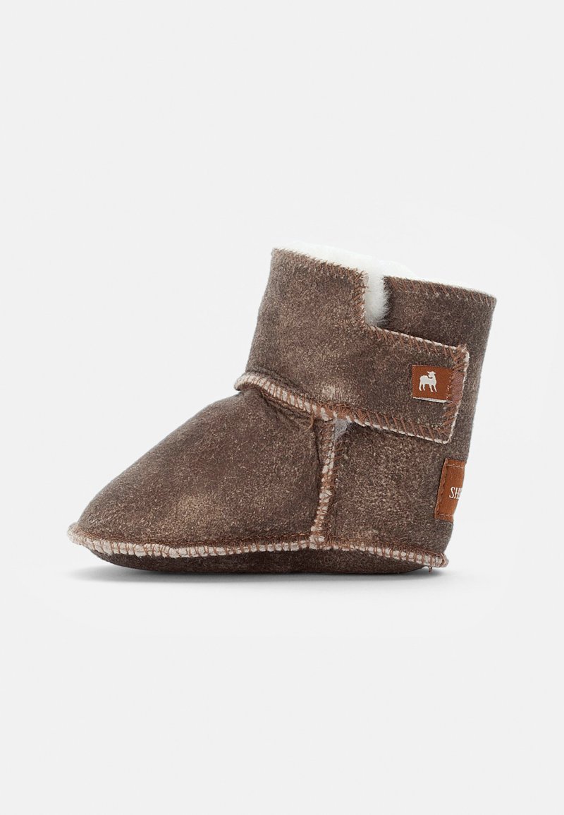Bota de camurça castanha com um forro branco suave, apresentando um design envolvente, costura em contraste e um detalhe de couro com marcação na lateral.