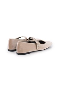 Bailarinas de terciopelo beige con punta redonda, dos tiras finas y suela de goma negra. Textura suave con detalles de costura mínimos.