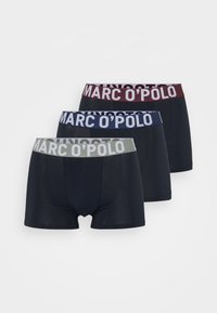 Három pár férfi alsónadrág sötét színekben, kontrasztos elasztikus derékszíjjal. A szalagok boldog betűkkel viselik a "MARC O'POLO" feliratot.