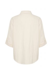 Camicia a maniche lunghe color crema con colletto, vista da dietro, con maniche arrotolate e vestibilità ampia.