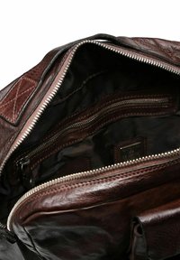 Bolso de cuero marrón con una abertura con cremallera, que cuenta con un interior de tela oscura, múltiples compartimientos y una textura suave. Detalles de costura sutil.