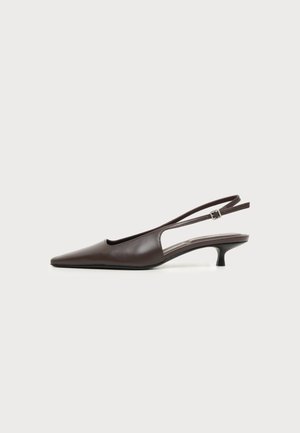 Σκούρο καφέ δερμάτινο παπούτσι με slingback, τακούνι kitten, μυτερή μύτη και ρυθμιζόμενο λουράκι αστραγάλου σε απλό ανοιχτό φόντο.