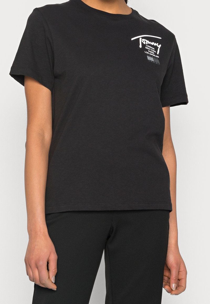 Svart bomullströja med korta ärmar. Har en vit logotyp och text på bröstet. Enkelt design med en avslappnad passform.