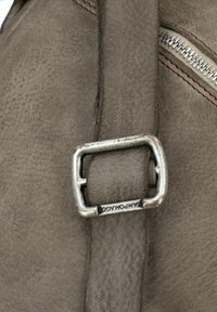 Borsa in pelle grigia con superficie testurizzata, caratterizzata da una fibbia in metallo argentato e dettagli di cucitura. Messa a fuoco ravvicinata sulla fibbia e sulla texture del materiale.