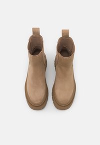 Botine din piele maro, cu o textură netedă, vârf rotunjit și talpă căptușită. Prezintă bandă de tragere în spate pentru un confort sporit la purtare.