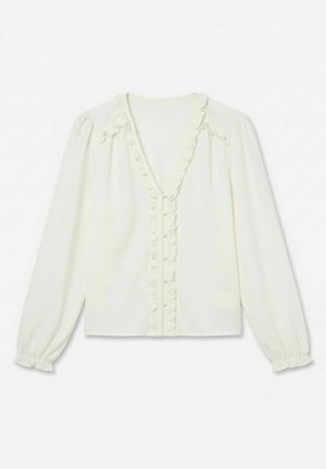 Blouse blanche à manches longues avec col en V, boutons recouverts de tissu sur le devant et détails à volants le long de l'encolure et des manches.