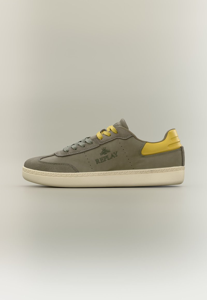 Baskets basses grises avec patch talon jaune et lacets jaunes, semelle crème et logo "REPLAY" sur le côté, présentées sur un fond neutre.