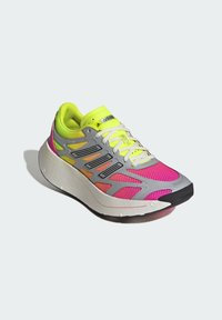 Gray athletic shoe with neon yellow and pink accents, mesh upper, patterned design, and a thick white sole. Features laces and branding on the tongue.