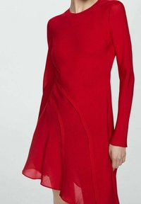 Vestido rojo de manga larga con un dobladillo ligeramente acampanado, que presenta tela transparente, costuras curvadas y un diseño minimalista.