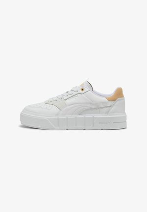 Zapatilla blanca de cuero con lengua acolchada, acentos de paneles texturizados y una suela intermedia blanca gruesa. Marca dorada cerca de los cordones para darle detalle.