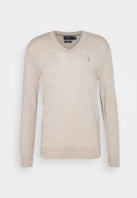 V-ringad, långärmad tröja i ljusbeige stickad tyg. Har en liten broderad logotyp på vänster bröst, ribbad avslutning och ärmslut.