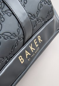 Musta kohokuvioitu nahkalaukku, jossa on monimutkainen hunnutussimulaatio, kiiltävät yksityiskohdat ja kultainen "BAKER by Ted Baker" -logo tekstuuripinnalla.