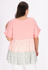 Pink rynket kortærmet bluse med lagdelt kant, prydet med leopardmønster i lyserød og grå. Blødt stof, afslappet pasform.