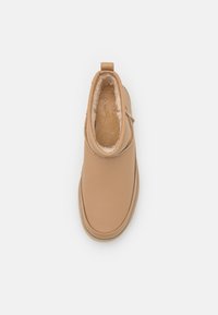 Stivale alla caviglia in pelle color tan con morbida fodera in pelliccia sintetica. Punta rotonda, cuciture minime e una linguetta sul retro per facilitarne l'indossamento.