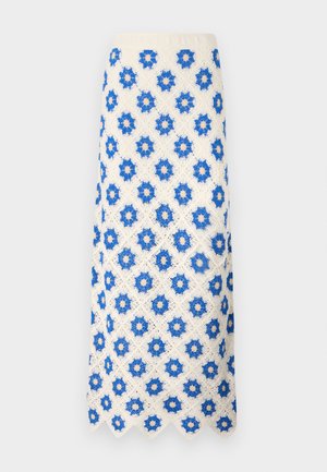 Jupe maxi en dentelle blanche avec des motifs floraux bleus. L'ourlet festonné et le design texturé ajoutent du détail au tissu.