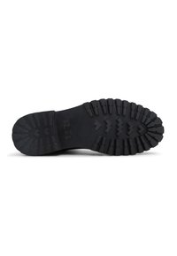 Suela de bota negra resistente con surcos profundos y "MR. B'S" grabado en el medio sobre un fondo blanco.