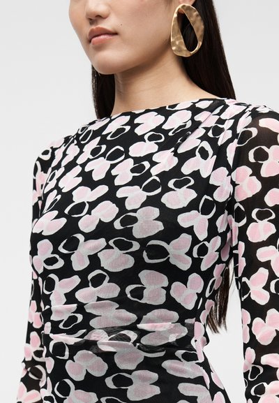 Vestido preto com padrão floral abstrato em rosa e branco, mangas compridas, textura suave; grandes brincos de argola dourados complementam o design.