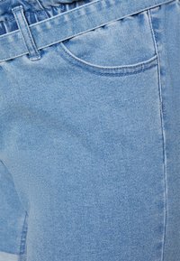 Calções de ganga azul claro com cintura elástica, apresentando um único bolso frontal e uma textura subtil, exibindo um corte clássico.