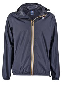 Námořnická modrá větrovka s kapucí, která má přední zip se žlutými a bílými pruhy, elastické manžety a volný střih.