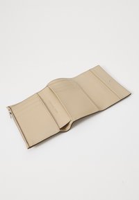Portefeuille en cuir beige, fermeture éclair, plusieurs compartiments pour cartes, texture lisse, design minimaliste, nom de marque embossé à l'intérieur.