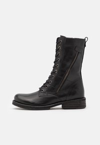 Botte montante en cuir noir avec lacets, fermeture éclair latérale, bout rond, talon texturé et œillets métalliques. Conçue pour le maintien de la cheville et la durabilité.