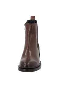 Brązowy skórzany botek sięgający kostki o gładkim wykończeniu, okrągłym nosku, z suwakiem po boku i paskiem ułatwiającym zakładanie. Solidna czarna gumowa podeszwa.