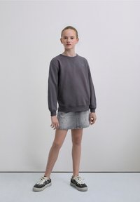 Gray sweatshirt with ribbed cuffs, crew neck, and embroidered logo, paired with a light denim mini skirt featuring subtle embellishments.