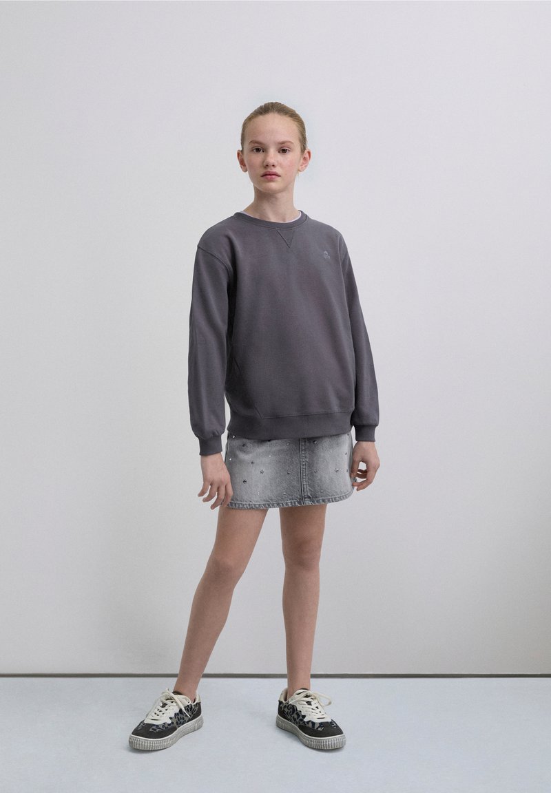 Gray sweatshirt with ribbed cuffs, crew neck, and embroidered logo, paired with a light denim mini skirt featuring subtle embellishments.