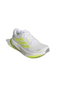 White sports shoe with a textured upper, neon yellow accents, three stripes logo, cushioned sole, and lace-up closure.