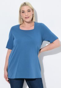 Modrý top s krátkým rukávem a čtvercovým výstřihem, vyrobený z měkké elastické látky. Volný střih s hladkým povrchem a neformálním designem.