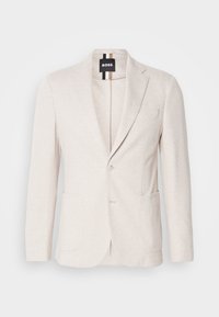 Blazer beige chiaro realizzato in tessuto texturizzato, con revers a punta, due tasche frontali e chiusura con un solo bottone. Etichetta del marchio visibile all'interno.