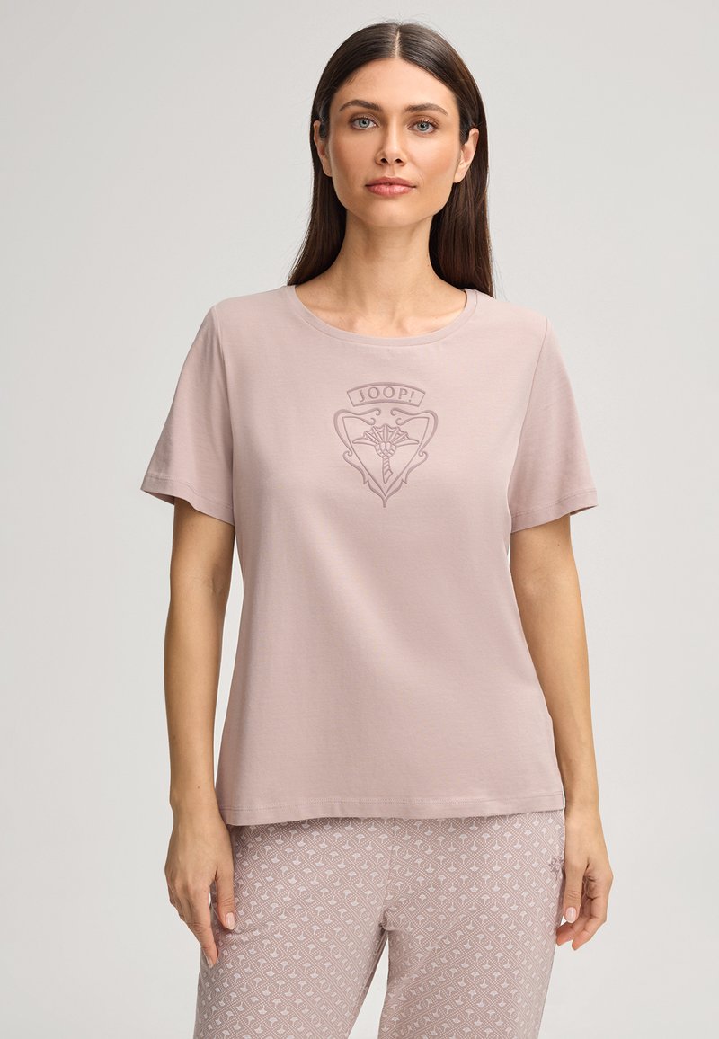 Vaaleanpunainen lyhythihainen T-paita pehmeästä kankaasta, jossa on pyöreä pääntie ja hienovarainen kohopainettu logokuvio rinnassa.