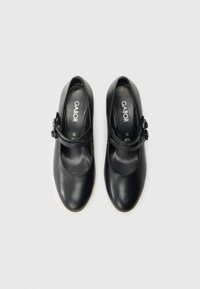 Mustat nahkaiset Mary Jane -kengät pyöristetyllä kärjellä, hihnalla, jossa pieni solki, ja sileä pinta. Sisäpuolella näkyy "Gabor"-logo.