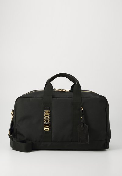 Sac de sport noir en nylon avec quincaillerie dorée, double poignées, bandoulière amovible et détail de logo sur le côté.