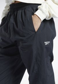 Mustat urheiluhousut, jotka on valmistettu kevyestä kankaasta. Housuissa on joustava vyötärö, sivutaskut ja vasemmassa reidessä Reebok-logo.