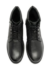 Czarne skórzane botki za kostkę z okrągłymi noskami, zaokrąglonymi krawędziami i wyściełanym kołnierzem; mają sznurowany design oraz teksturowaną powierzchnię.