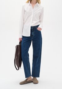 Biała koszula z guzikami, niebieskie dżinsy z wysokim stanem, brązowa torba na ramię i brązowe buty wsuwane. Prosta tkanina, luźny krój, minimalistyczny design.