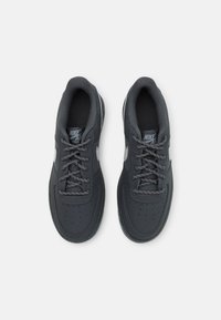 Zapatillas Nike Air Force negras con cordones grises, parte superior de cuero liso, caja de dedos perforada y distintivo logo Swoosh blanco en los laterales.