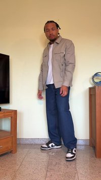 Casaco abotoado cinza claro, t-shirt branca por baixo, calças de ganga azuis e ténis preto e branco. Textura suave, corte relaxado.