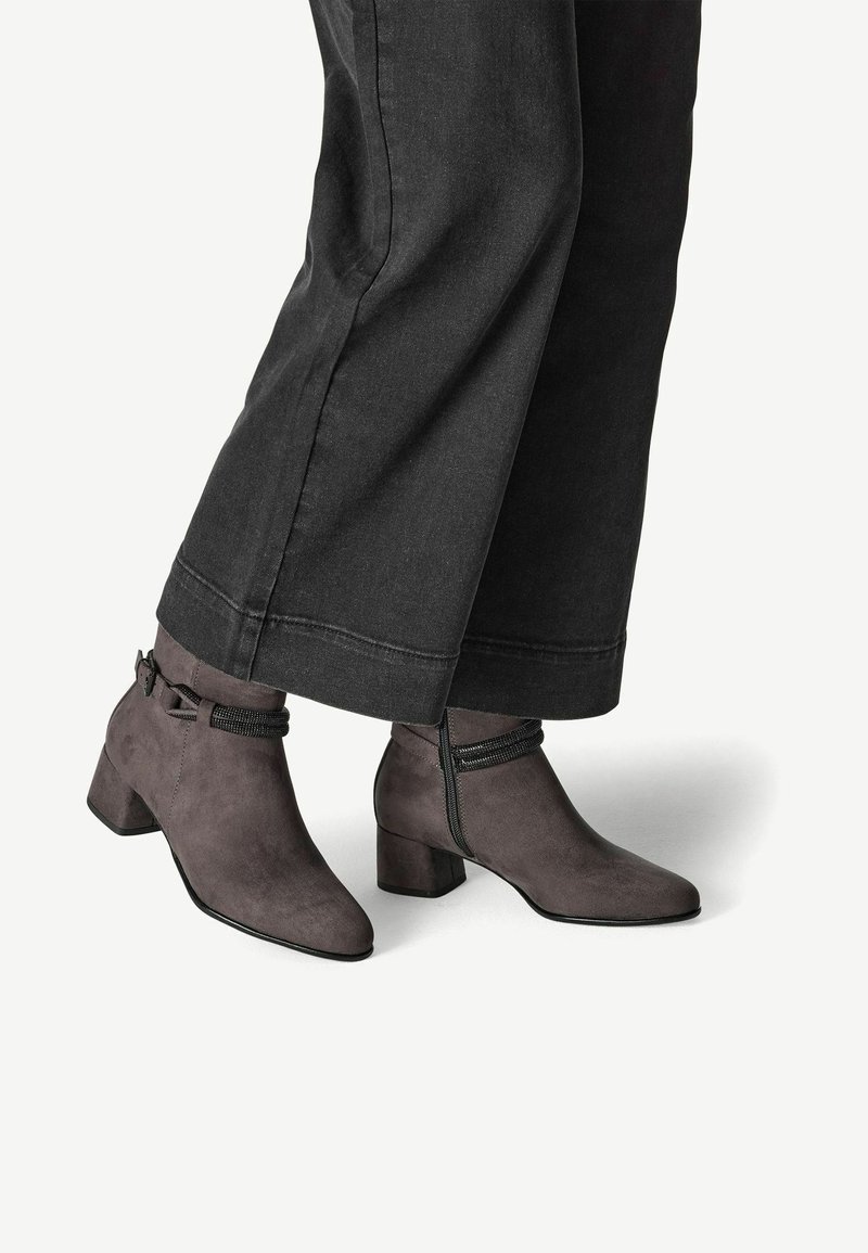 Bottines en daim gris avec talons blocs et fermetures éclair latérales portées avec un pantalon large noir.