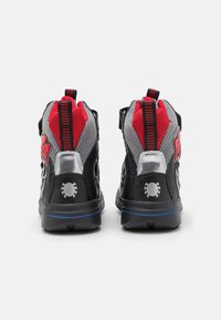 Mustat ja punaiset kengät, joissa on verkkomateriaalia ylempänä, pyöreä kärki ja kuvioitu pohja. Ominaisuuksiin kuuluu kontrastiväriset kantakoristeet ja logomallit.