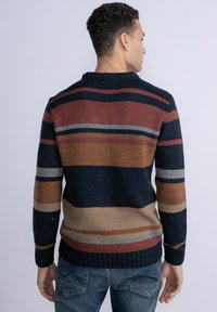 Gehaakte trui met een ronde halslijn, gekenmerkt door horizontale strepen in marineblauw, roest, beige en grijs, met ribgebreide zoom en manchetten.