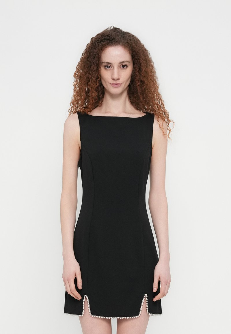 Zwarte mouwloze jurk met een rechte halslijn, getailleerde vorm en een gekartelde zoom versierd met kralen. Gladde stoftextuur.