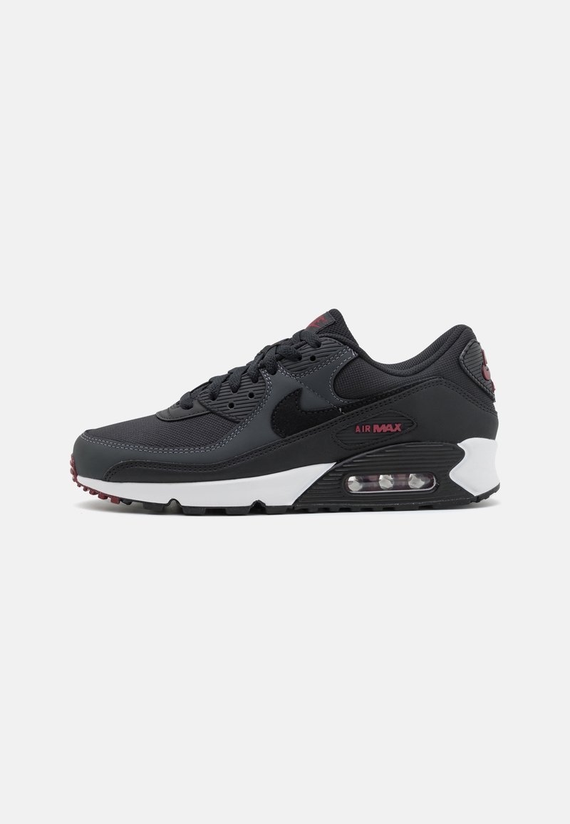 Baskets de sport noires avec un dessus en maille et en synthétique, dotées d'une semelle intermédiaire blanche, d'un amorti à air visible et d'accents rouges sur la marque.