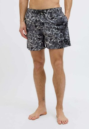 Costume da bagno a motivi in bianco e nero con vita elasticizzata e cordoncino. Presenta tasche laterali e una patch del logo sull'orlo.