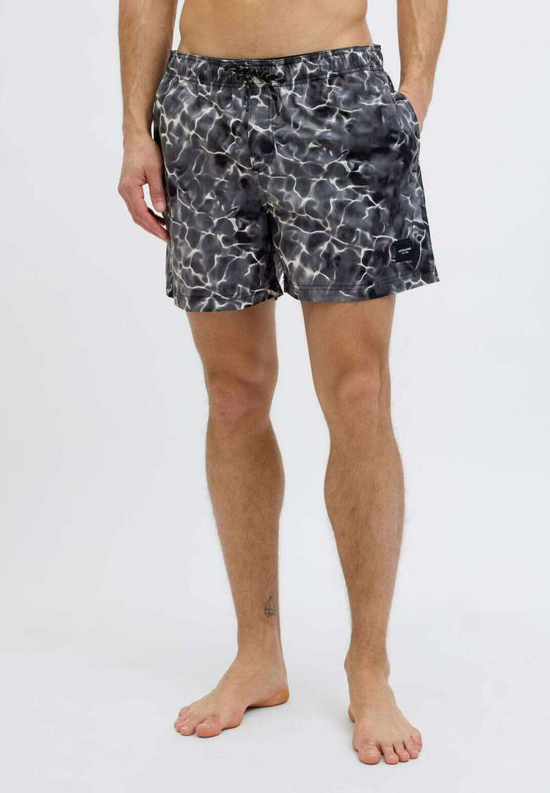 Costume da bagno a motivi in bianco e nero con vita elasticizzata e cordoncino. Presenta tasche laterali e una patch del logo sull'orlo.