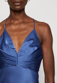 Rochie din satin în nuanțe de albastru închis, cu decolteu în V, bretele subțiri și textură plisată la bust pentru o siluetă ajustată.