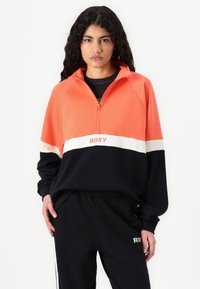 Oranžová a čierna polovične zipsová mikina so bielym prúžkom a textom "ROXY". Vyrobená z mäkkej látky, so voľným strihom a dlhými rukávmi.