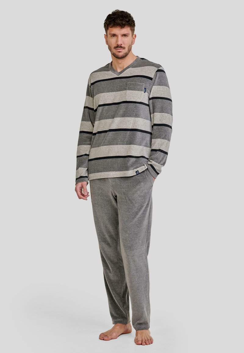 Camisa de manga larga a rayas grises con bolsillo, combinada con pantalones grises. Tejido suave, corte holgado y color sólido con rayas negras de contraste.
